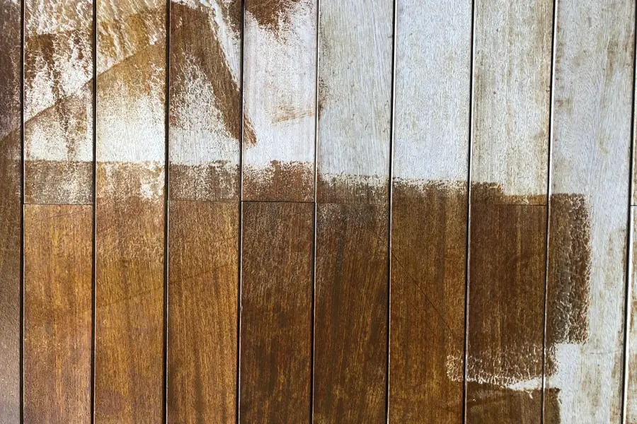 Wood fence boards partly coated with fresh white paint