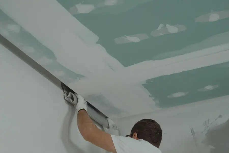 Worker scraping and prepping a ceiling before refinishing