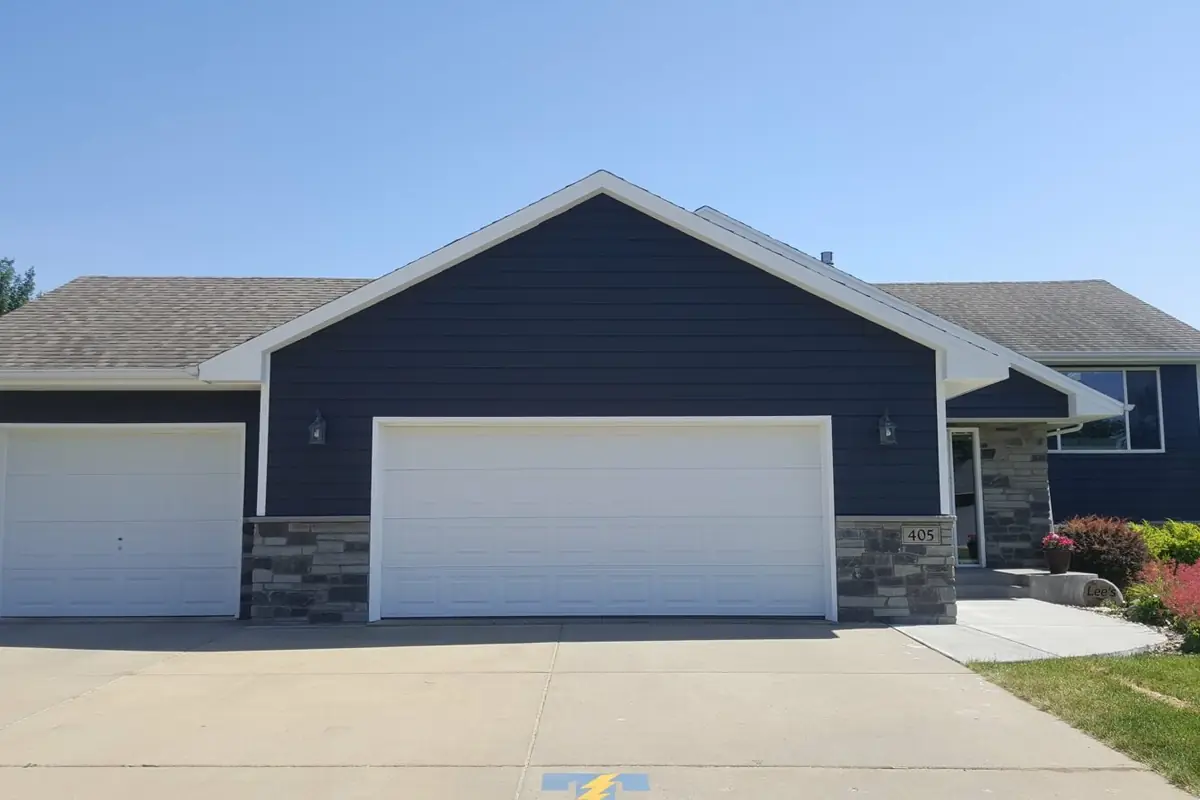 Exterior repaint of a navy-blue ranch home with white garage doors and trim